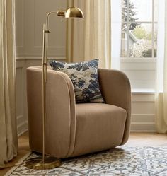 a living room with a chair, lamp and rug in front of a window on the floor