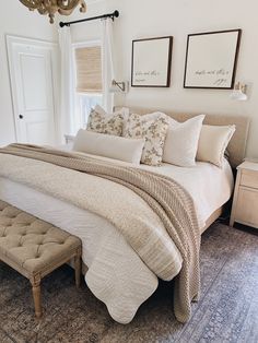 a bedroom with a large bed covered in white blankets and pillows next to a window