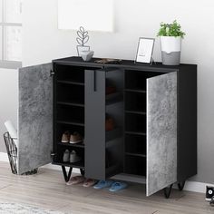 an open cabinet with shoes on it next to a potted plant