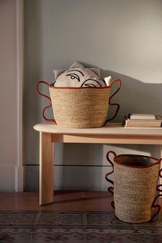 two baskets sitting on top of a wooden table next to a book shelf with books