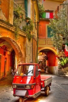 an old red truck is parked on the street in front of a building with balconies