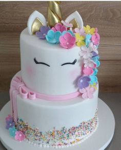 a white cake decorated with flowers and a unicorn face