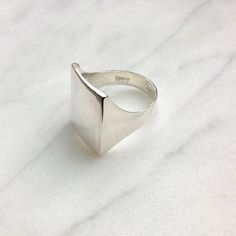 "Hand carved slightly rectangular square shaped ring is modern and great for everyday. Smooth solid handmade ring is made with a comfort fit. Carved out of wax and casted into Sterling Silver, sculpted to fit close and thinly around the finger, for a natural comfortable fit. Shown here with a polished/ shiny finish. Inside ring stamped with logo. Measurements: 3/4\" front of ring - top to bottom 5/8\" front of ring wide  3/16\" back of ring (tapers to) Available in matte or shiny finish / comes automatically in shiny, if you prefer matte, please add to notes section of order. HANDMADE JEWELRY - sarah healy studio SARAHHEALYDESIGN.COM Made in USA" Modern Everyday Rings With Rectangular Stone, Modern Everyday Ring With Rectangular Stone, Modern Wide Band Signet Ring For Everyday, Modern Square Cut Signet Ring As Gift, Handmade Rectangular Minimalist Rings, Minimalist Rectangular Ring With Polished Finish, Rectangular Modernist Signet Ring With Polished Finish, Square Signet Ring, Minimalist Silver Square Ring