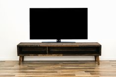 a flat screen tv sitting on top of a wooden entertainment center in front of a white wall