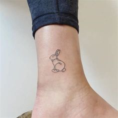 a small tattoo on the ankle of a woman's foot, with a rabbit