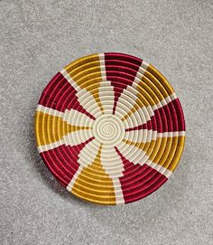 a red, yellow and white basket sitting on top of a gray floor next to a wall