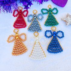 six beaded christmas ornaments on a white surface next to purple and red tinsel