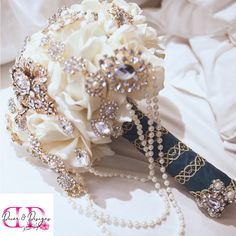 a bridal bouquet with pearls and brooches sits on a white bed sheet