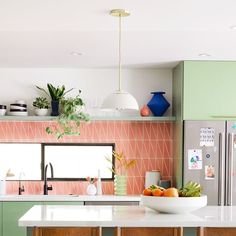 a kitchen with green cabinets and pink tiles on the backsplash, white countertops and wooden stools