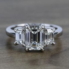 an emerald cut diamond ring on a wooden table