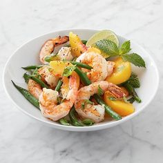 a white bowl filled with shrimp and veggies on top of a marble counter