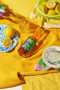 a table topped with lemons and bottles of alcohol on top of a yellow cloth