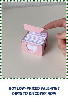 a hand holding a pink box with white paper in it and the words hot low - priced valentine gifts to discovery now