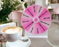 a cup of coffee sitting on top of a table next to a pink spinning wheel