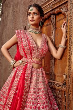 Coral lehenga with gota patti trims, beads and crystal work. Comes with blouse and dupatta.
Component: 3
Pattern: Embroidered
Type Of Work: Gota Patti, Beads and Crystal
Neckline: V neck
Sleeve Type: Sleeveless
Fabric: Raw Silk and Tulle
Color: Pink
Other Details: 
Bead hangings
Back with criss cross straps
Note: Belt worn by the model is not for sale
Occasion: Bride - Aza Fashions Pre-draped Anarkali Saree With Gota Work, Dola Silk Lehenga With Mirror Work, Anarkali Lehenga With Mirror Work In Dola Silk, Festive Kundan Lehenga With Dupatta, Traditional Drape Choli With Gota Work For Reception, Festive Kundan Anarkali Pre-draped Saree, Designer Kundan Choli For Eid, Eid Bollywood Style Lehenga With Gota Work, Red Lehenga With Mirror Work In Chinon