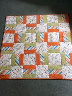 an orange and white patchwork quilt on a gray floor with polka dots, stripes, and strips