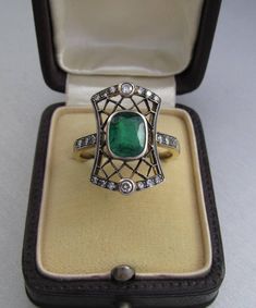 Art Deco emerald ring with diamonds, made of 14K gold and silver. With a Hungarian 14K hallmark that was used after 2016. The top part is made of silver. The head part of the ring is 0.796 inches (20 mm) long. Gemstone: one piece of emerald, 1.54 carat, its size is: 0.24 inches * 0.31 inches (6.1 mm * 7.8 mm) The emerald has inclusions which unfortunately affects the surface of the stone as well. I tried to make photos of that. Additional gemstone details: 20 single cut diamonds Carat weight: 0. Elegant 14k Stamped Emerald Ring, Formal Emerald Ring With Intricate Design, Emerald Ring With Rose Cut Diamonds For Formal Occasions, Emerald Rings With Single Cut Diamonds For Gifts, Heirloom Green Ring With Diamond Accents, Heirloom Green Rings With Diamond Accents, Art Deco Emerald Ring As Gift, Formal Emerald Cut Emerald Ring With Rose Cut Diamonds, Art Deco Emerald Ring For Gift