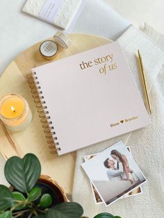 the story of us book next to a candle and potted plant on a table