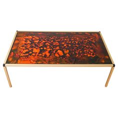 a coffee table with an orange and black painting on it's surface, against a white background