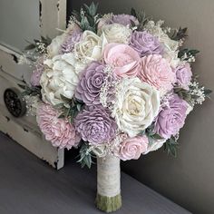 a bridal bouquet sitting on top of a table next to an open door with white and pink flowers