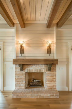 a brick fireplace with two lights on each side and wood beams above the fire place