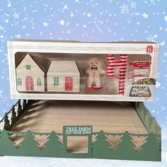 an open box with christmas decorations in it on top of a snow covered ground and trees