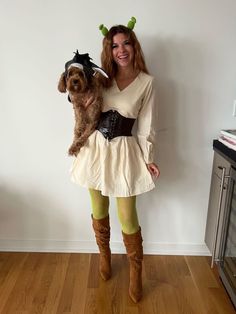 a woman holding a dog in her arms and wearing a costume with horns on it's head