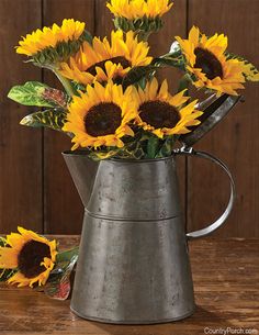 a metal watering can with sunflowers in it