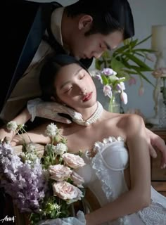 a bride and groom are posing for a wedding photo with flowers in front of them