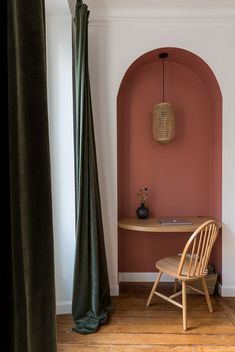 a wooden chair sitting in front of a pink wall