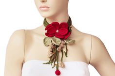 a woman wearing a white top and red flowers on her neck with green leaves attached to it