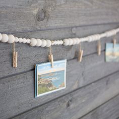 several pictures hanging from clothes pins on a wooden board with string attached to it and two photos pinned to the pegs