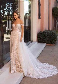 a woman in a wedding dress is standing on the steps outside her store front door