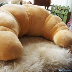 a large stuffed animal laying on top of a white fluffy rug next to a clock