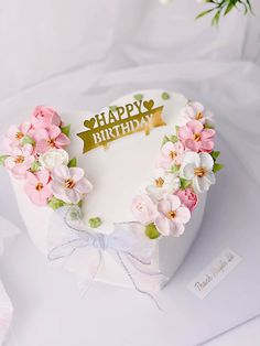 a birthday cake decorated with pink flowers and a gold happy birthday sign on the top