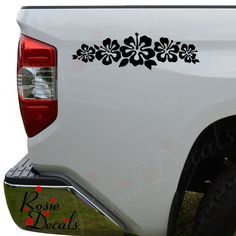 a white truck with black flowers on the tailgate and side decals in front of it