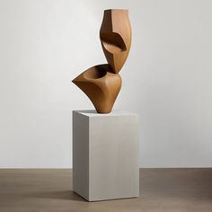 a wooden sculpture sitting on top of a white pedestal