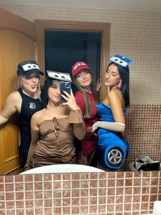 three women in costumes taking a selfie in a bathroom mirror with one holding up a cell phone