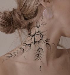 a woman's neck is adorned with black and white flower tattoo designs on her left side