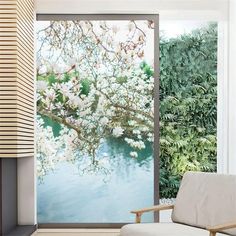 a white chair sitting in front of a window next to a wall with flowers on it