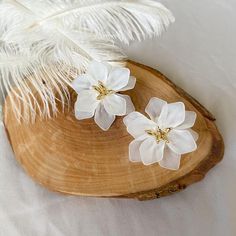 two white flowers sitting on top of a wooden plate