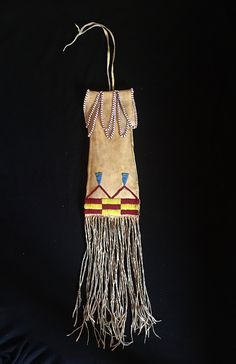 -This piece is a non-native tribute to the Arapaho Nation, faithfully and respectfully recreated in the traditional ways. Now showing our first ever Arapaho style tobacco bag. Beautifully crafted, and adorned with traditional colors and detail. Starting with a top quality deer hide and stitched in sinew. Six finger flaps at the top of the bag, meticulously beaded in white and deep red.  A bar pattern across the bags base, front and back, with distinct colors on both sides. A stunning display of twisted fringe along the bags base.  Aged  to antiquity, making an exquisite display of Native American heritage. The bag portion of this piece measures roughly 14" x 6", with a total length of roughly 28 inches. -Artistic Expressions Traditional Handmade Brown Pouch, Traditional Brown Rectangular Pouch, Beaded Pouch Bag, Native Artifacts, Indian Beadwork, Beaded Pouch, Native American Crafts, Painted Bags, Native Beadwork