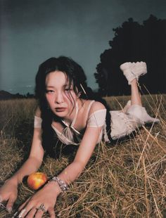 a woman laying on the ground with an apple in her hand and wearing bracelets