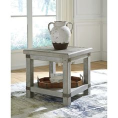 a white vase sitting on top of a wooden table next to a window in a living room