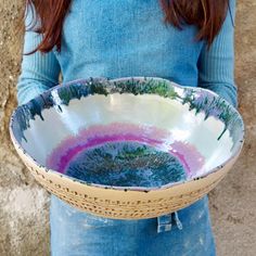 a woman holding a bowl with trees painted on it