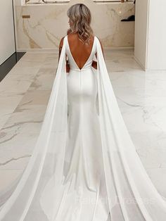 a woman in a white wedding dress with a long cape on her head and back