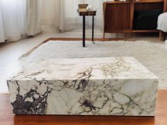 a white marble box sitting on top of a wooden floor next to a rug and table