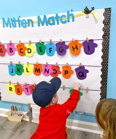 a little boy that is standing in front of a bulletin board with letters on it