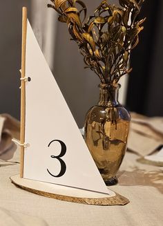 there is a vase with flowers in it and a sail boat on the table next to it