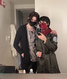 two people wearing masks taking a selfie in the mirror